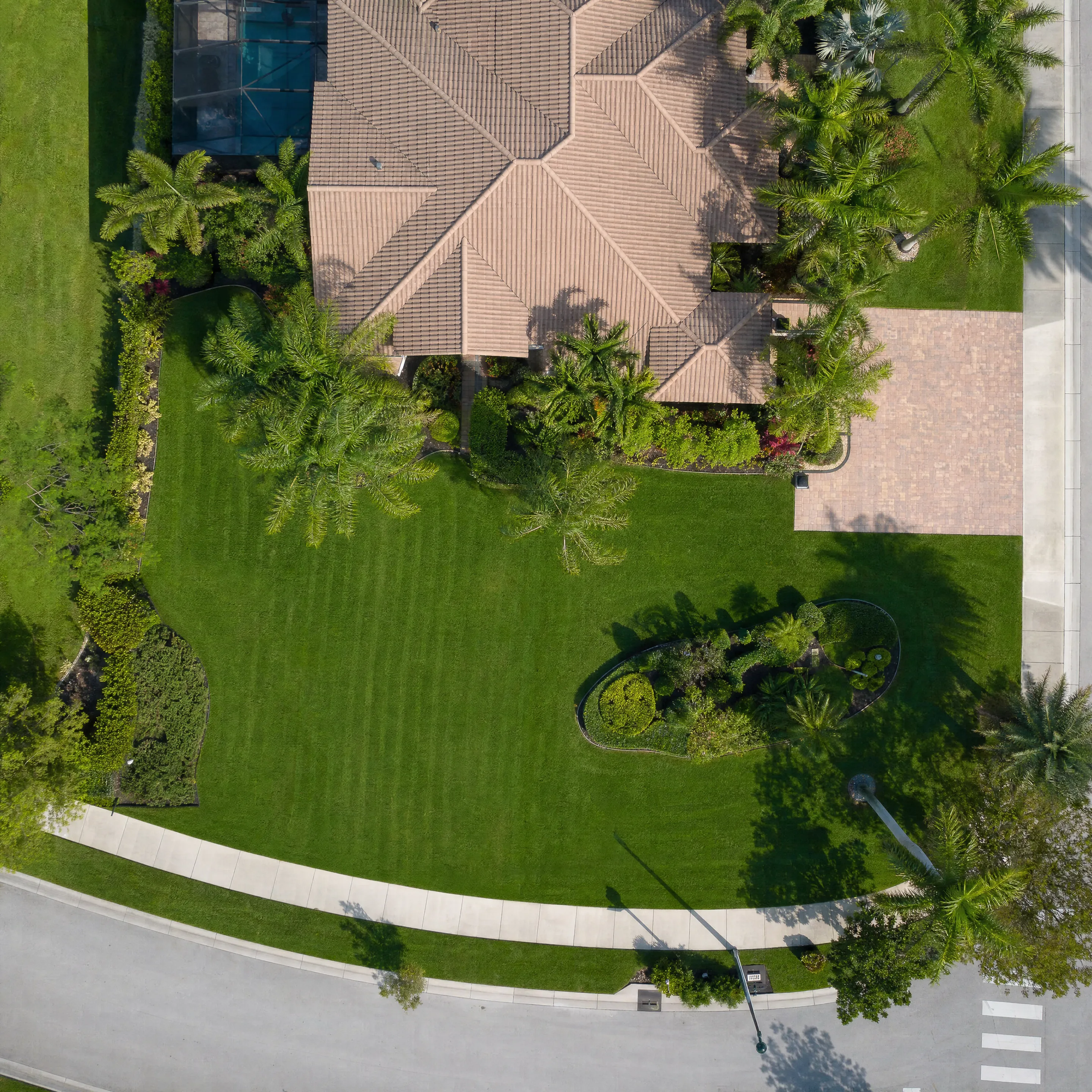 An overhead aerial of a residential property with pool and full green lawn
